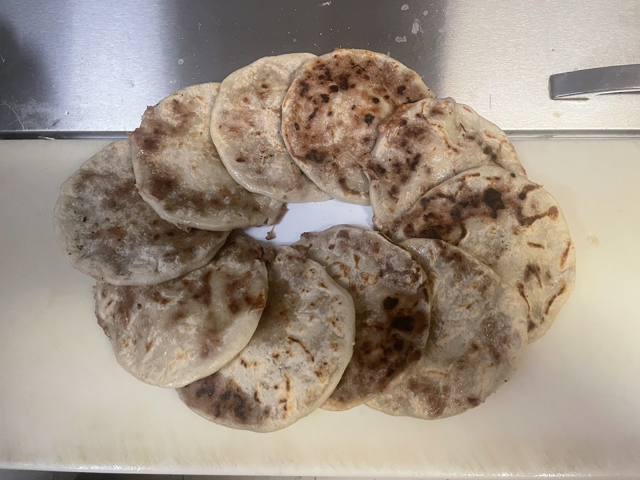 A fresh batch of hand-pressed pupusas on the griddle board at Taso's