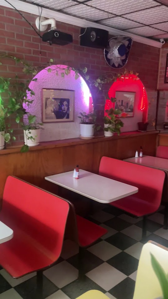 Inside Taso's — red booths, plants and framed art under warm lighting